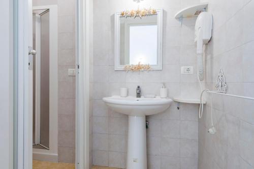 a white bathroom with a sink and a mirror at Calliope's Apartments - Stella del Mare in Siracusa