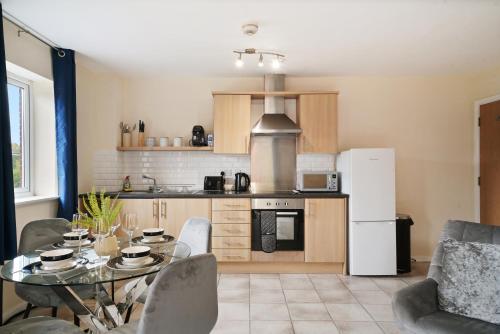 a kitchen with a table and a white refrigerator at Peaceful 2BR Flat with Historic Bottle Kilns View & Free Parking Located near City Centre in Stoke on Trent