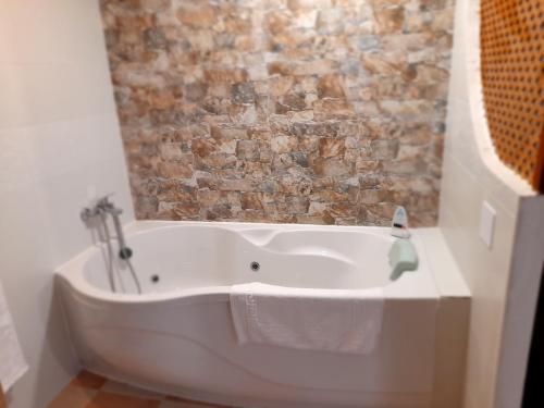 y baño con bañera blanca y pared de ladrillo. en Room in Lodge - Rural Hotel Las Quintas de los Mangas Verdes, en Quintana Redonda