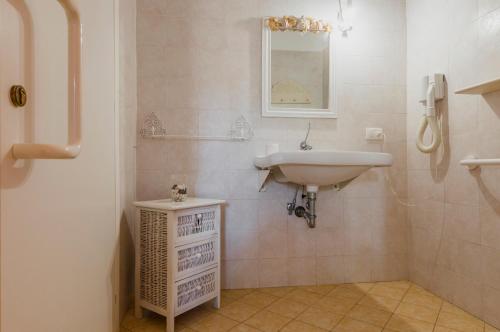 a white bathroom with a sink and a mirror at Calliope's Apartments - Stella del Mare in Siracusa