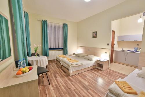 a hotel room with two beds and a table with a bowl of fruit at Parkowy Dworek in Rabka-Zdrój