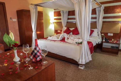 Bharatpur Garden Resort في بهاراتبور: غرفة نوم مع سرير مع كؤوس للنبيذ على طاولة
