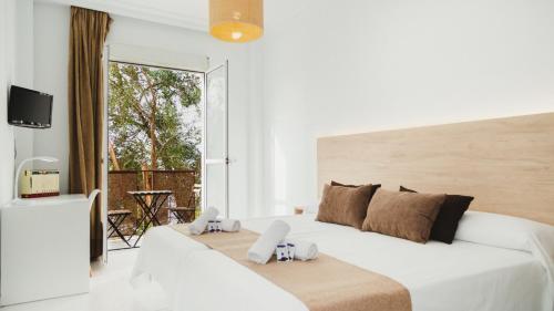 a white bedroom with a large bed and a balcony at Hotel Olive in Osuna
