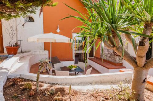 a patio with a table and an umbrella and palm trees at Calliope's Apartments - Stella del Mare in Siracusa