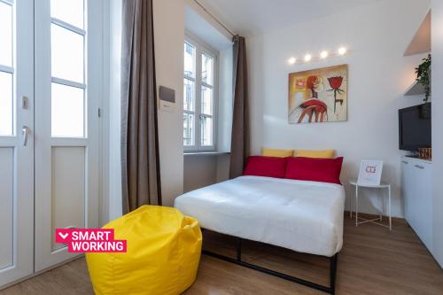 ein kleines Schlafzimmer mit einem Bett und einer gelben Ottomane in der Unterkunft Porta Susa Studio Apartment by Wonderful Italy in Turin