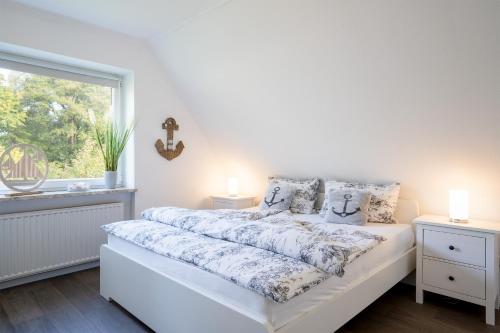 a white bedroom with a bed and a window at MiBa Mare Ferienwohnung "Sol" in Scharbeutz