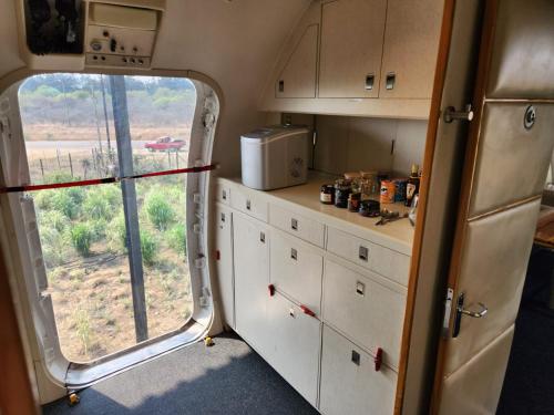 a kitchen with white cabinets and a large window at AEROTEL VIP in Hoedspruit