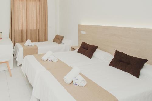 Dos camas en una habitación de hotel con zapatillas. en Hotel Olive, en Osuna