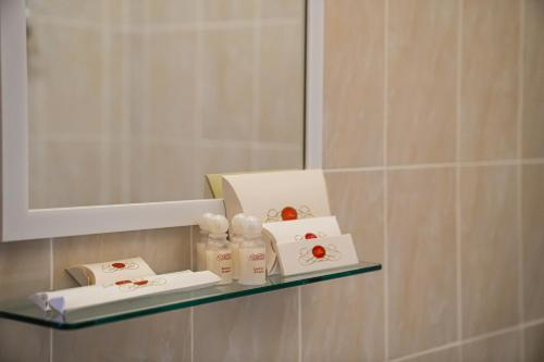 a shelf in a bathroom with bottles of soap and a mirror at Belon Lux Hotel in Astana
