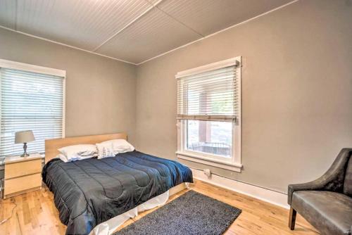 a bedroom with a bed and a chair and two windows at Historic Apartment - Walk to CSU Campus and Old Town in Fort Collins
