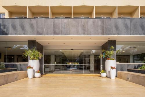 a lobby with white vases with plants in them at Sol Palmanova Mallorca in Palmanova