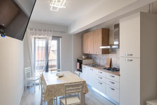 una cocina con armarios blancos y una mesa con sillas. en Appartamento Moderno in Centro città en SantʼAgata di Militello