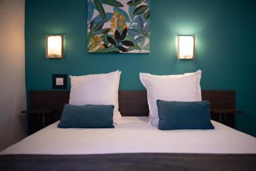 a bedroom with a bed with two blue pillows at Hotel de Normandie in Lyon