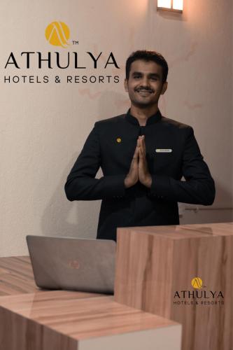 a man standing in front of a table with a laptop at Athulya Residence Suite Rooms in Bengaluru
