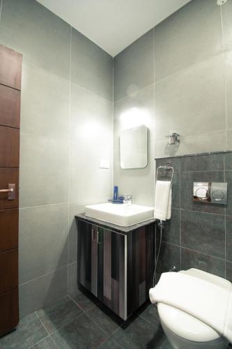 a bathroom with a white sink and a toilet at Athulya Residence Suite Rooms in Bengaluru