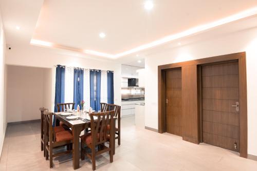 a dining room with a table and chairs and a kitchen at Athulya Residence Suite Rooms in Bengaluru