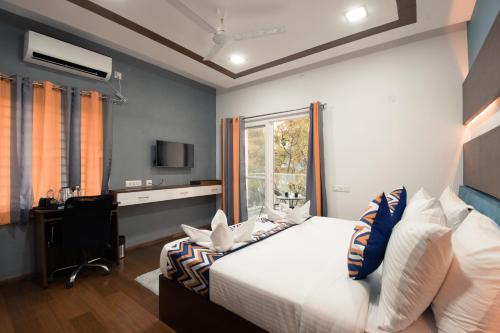 a bedroom with a bed and a desk and a window at Athulya Residence Suite Rooms in Bengaluru