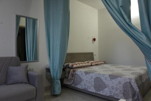 a bedroom with a bed with blue curtains and a chair at Sognando nel borgo in Rocca Imperiale