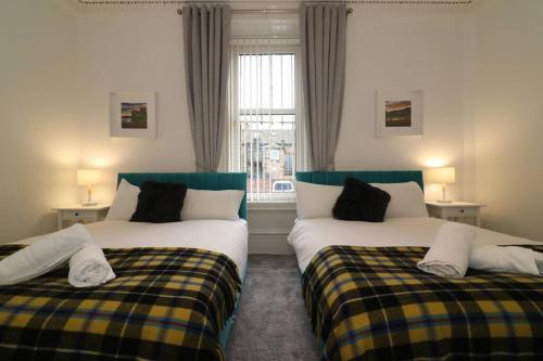 Duas camas num quarto com uma janela em 10 Bedrooms Pool Table Garden Piano em Glasgow