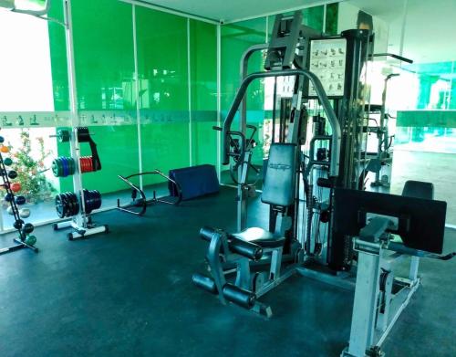 a gym with cardio equipment in a green room at Ancorar flat resort paradise in Porto De Galinhas