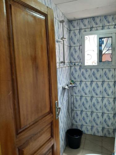 La salle de bains est pourvue d'une porte en bois et de toilettes. dans l'établissement Signorile Jo, à Yaoundé