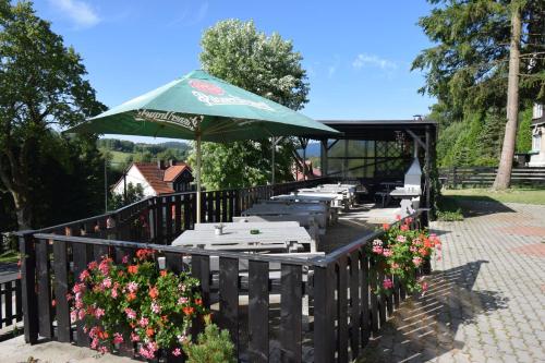a patio with tables and a green umbrella and flowers at Pension St. Moritz in Železná Ruda