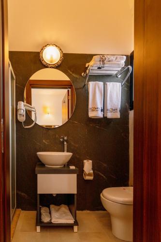 a bathroom with a sink and a mirror and a toilet at Cezar's Airport Hotel in North Nicosia