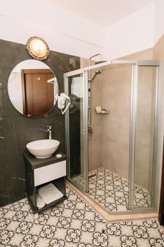 a bathroom with a shower and a sink and a mirror at Cezar's Airport Hotel in North Nicosia