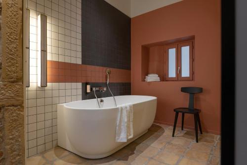 La salle de bains est pourvue d'une baignoire et de murs orange. dans l'établissement MiHotel Saint Jean, à Lyon