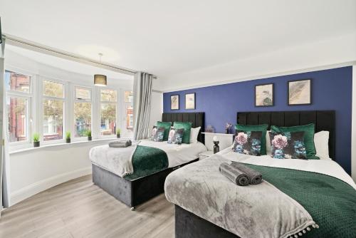 2 camas en una habitación con paredes y ventanas azules en Stylish 4 Bed House in Nottingham - sleeps 15, en Nottingham