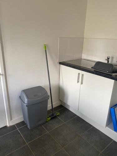 a bathroom with a trash can and a mop at Lodge 4, The Grange, 53 High Street, Wick, Bristol BS30 5QQ in Wick