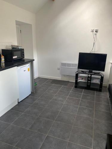 a living room with a television and a tiled floor at Lodge 4, The Grange, 53 High Street, Wick, Bristol BS30 5QQ in Wick