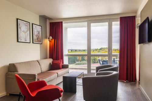 a living room with a couch and chairs and a large window at Novotel Senart Golf De Greenparc in Saint-Pierre-du-Perray