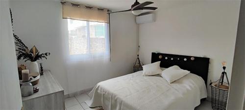 a bedroom with a bed with white sheets and a window at T2 Zen Évasion tout confort climatisé Saint Denis in La Montagne