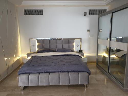 a bedroom with a large bed with a blue blanket at Deir Ghbar-Studio in Amman