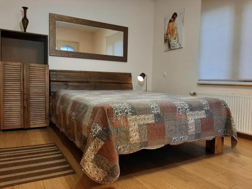 a bedroom with a bed with a blanket and a mirror at Champêtre Park View Apartments in Rīga