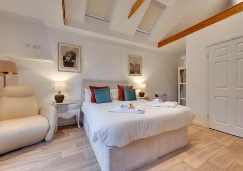 a bedroom with a large white bed and a chair at Malt Hall in Llanrhidian