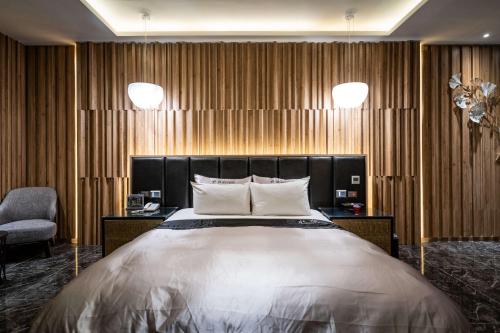 a bedroom with a large bed and a chair at Aquarius Motel in Taichung