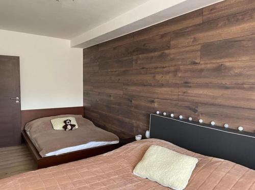 a bedroom with two beds and a wooden wall at Apartmán s nádherným výhľadom na Tatry in Veľký Slavkov