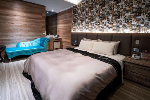 a bedroom with a large bed and a blue chair at Aquarius Motel in Taichung