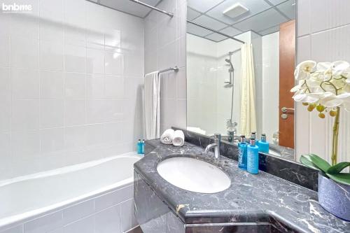 a bathroom with a sink and a bath tub at bnbmehomes - Cosy Downtown Apt w Balcony Near Metro Station -1710 in Dubai