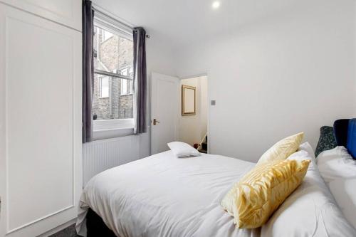 um quarto com uma cama branca e uma almofada amarela em Immaculately presented 1 bed em Londres