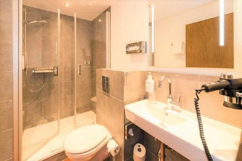 a bathroom with a shower and a toilet and a sink at IVY Hotel in Wolfsburg