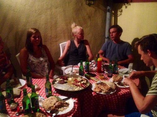 a group of people sitting around a table with food at Hostel David in Mostar