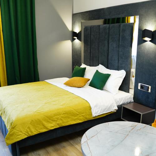 a bedroom with a large bed with yellow and green pillows at Гостинично-банный комплекс PARADISE in Shchūchīnsk