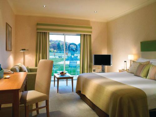 ein Hotelzimmer mit einem großen Bett, einem Schreibtisch und einem Schreibtisch in der Unterkunft Donnington Valley Hotel, Golf & Spa in Newbury
