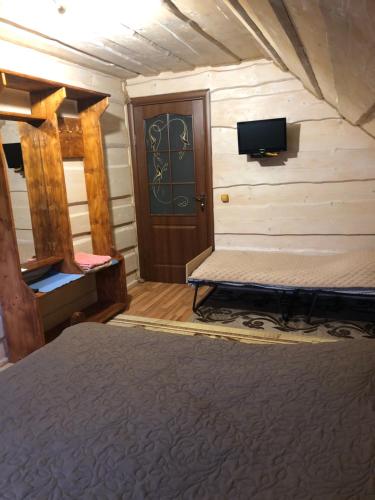 um quarto com uma cama e uma televisão na parede em Біля комори em Pilipets