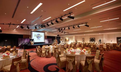 a banquet hall with tables and chairs and a screen at Hard Rock Hotel Penang in Batu Ferringhi