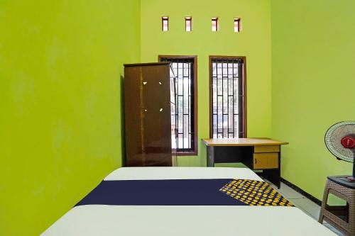 Habitación verde con cama y escritorio. en OYO Life 91869 Insan Mulia Kost Syariah, en Mojokerto