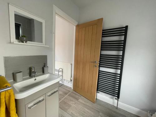 LincolnshireにあるWindmill View Apartmentsのバスルーム(シンク、木製のドア付)